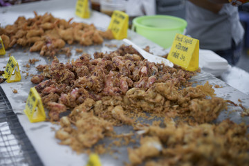 Fried little squid at thai market style with a yellow card of name of this food and price , selective focus, filtered image