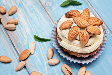 Fototapeta na wymiar Vanilla cupcakes with almonds on a blue wooden background