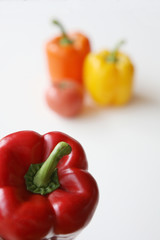 Three colored bell peppers and one tomato