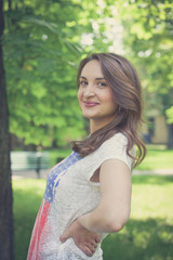 Obraz premium Beautiful sexy young hipster girl outdoors.Posh woman with long brunette hair evening makeup wearing jeans and vans sneakers posing outdoors in the city urban style in summer