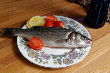 Sea bass, spigola. Fresh fish with the head on plate.
