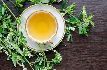 herbal sweetclover tea in a porcelain cup on a dark wooden background
