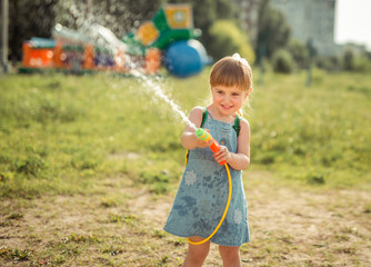 cute little girl playing water gun with hose outside