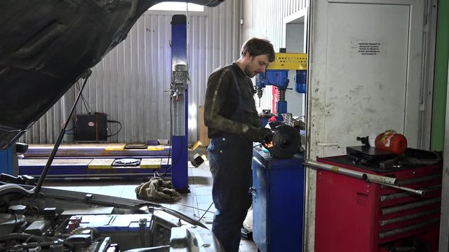 Mechanic guy polishing metal part on polishing machine