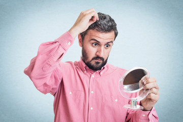Man worried about gray hair looking in a mirror