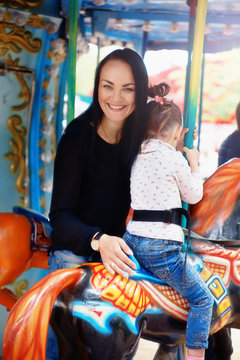 Mom and daughter in the park and ride on the carousel