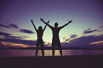 Naklejka na ściany i meble Couple enjoying on the beach in sunset / sunrise time.
