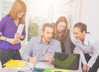 Obraz premium Young group of people discussing business plans, with lap-tops in a small office.