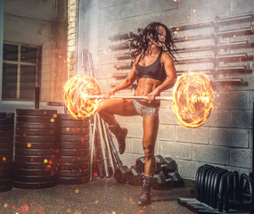 Brunette fitness woman exercising with burning barbell.