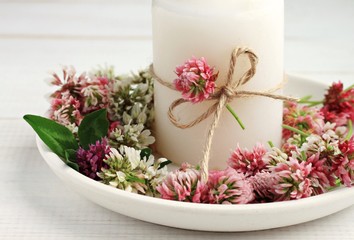 Fototapeta na wymiar Summer handmade simple candlestick decor. Candle and fresh meadow clover flowers. 