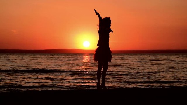 The girl dances on the beach at sunset. Slow motion
