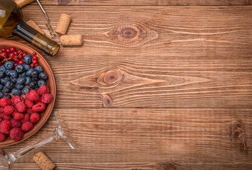 Bottle of wine with berries and corks on wooden table. Background.