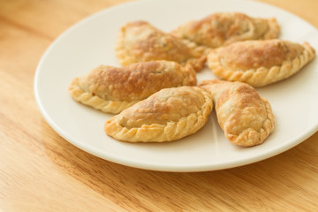 Empanadas argentinas sobre un plato redondo blanco sobre una mesa de madera rústica. Vista superior
