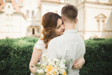 Beautiful fairytale newlywed couple hugging near old medieval castle