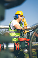 Engineer in worker's gear inspecting a valve