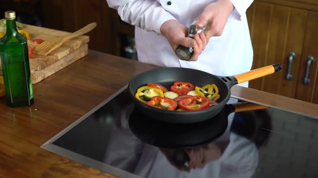 Professional chef cook peppers vegetables while cooking on the frying pan 