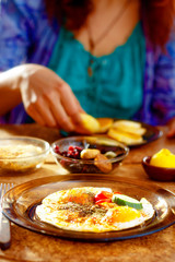 breakfast table setting with scrambled eyes and girl on the background.
