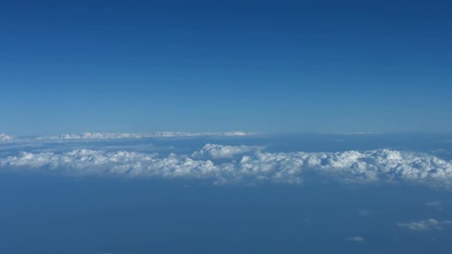 Video UHD - Airborne shot of a layer of puffy, white, cottony clouds, drifting over a vast epanse of open ocean far below.