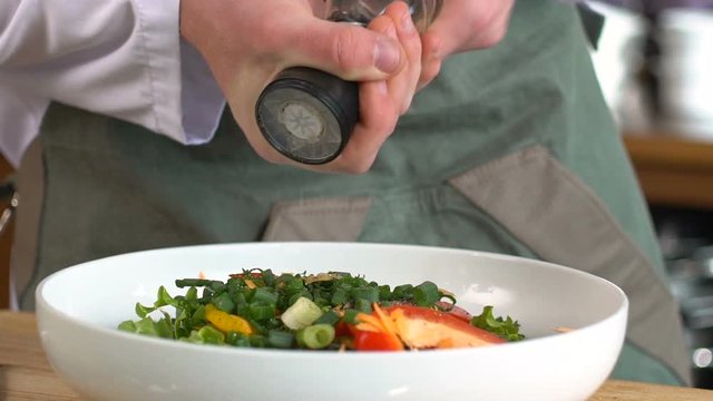 Professional chef cook peppers salad in a bowl on the wooden table