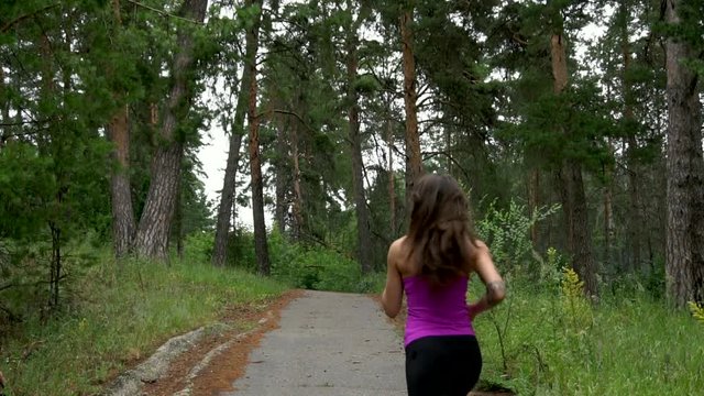 Sporty girl runs through the park in the morning. Slow motion. Full HD