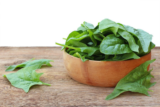 Spinach in wooden plate on an old wooden background isolated on