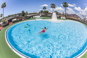 BOY HAS FUN SWIMMING ON A SURF BOARD IN THE POOL