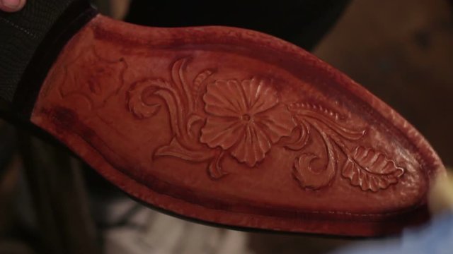 Painting sole for men shoes. Shoemaker sews shoes