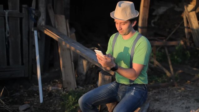 Young man making video call at sunset. A man sits at the sawmill
