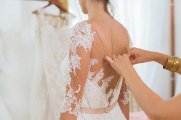 A young bride being helped into her wedding dress - obrazy, fototapety, plakaty