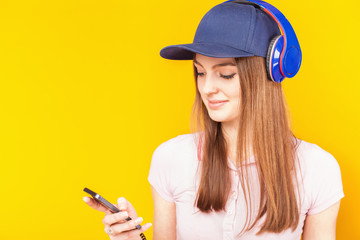 Surprised teenage girl uses a headphones and mobile phone