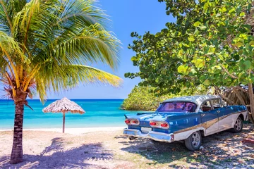 Foto op Plexiglas Uitstekende Amerikaanse oldtimerauto geparkeerd op een strand in Cuba © Delphotostock
