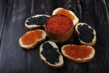 red and black caviar with bread on wooden background