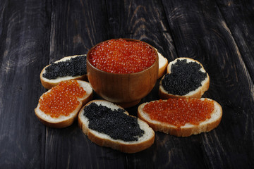 red and black caviar with bread on wooden background