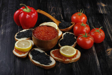 red and black caviar with bread and vegetables on wooden background 