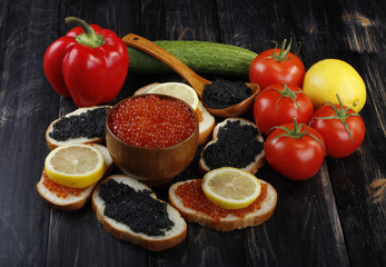 red and black caviar with bread and vegetables on wooden background 