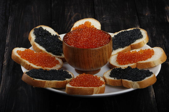 red and black caviar with bread on wooden background 