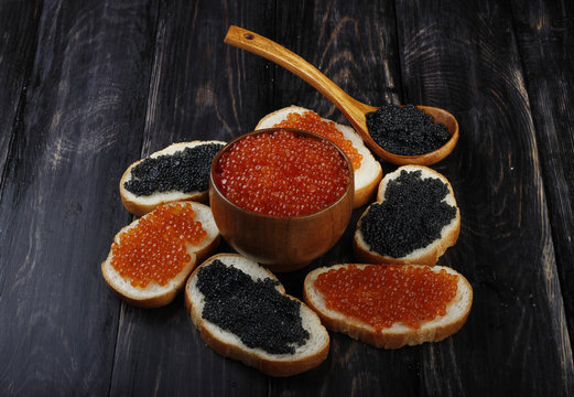 red and black caviar with bread on wooden background