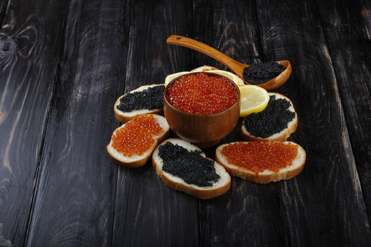 red and black caviar with bread on wooden background