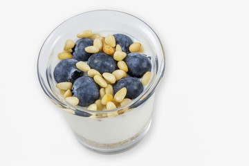 Glass of white yogurt with blueberries and pine nuts on the white background