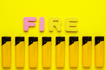 disposable plastic lighters and word fire on yellow background