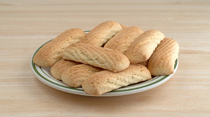 Vanilla cookie bars on a green striped plate atop a wood table.