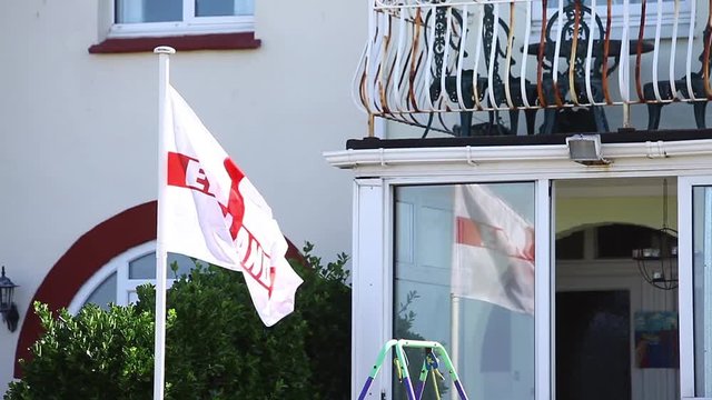 Color footage of the English flag, waving in front of a building.