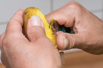 Eine Frau pellt und schält Pellkartoffeln mit einem Messer © mirkograul