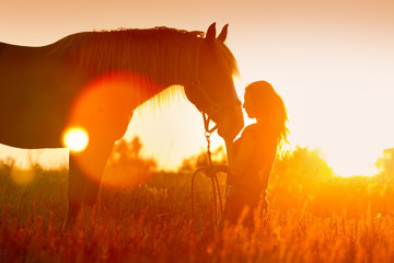 Naklejka premium Piękny silhuette dziewczyny i konia o zachodzie słońca