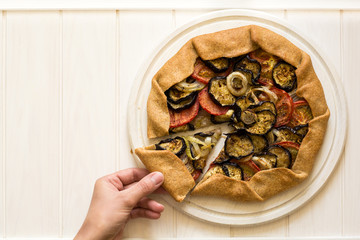 Homemade galette pie with grilled eggplants, tomatoes and onion on wooden background. Top view