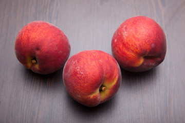 Fototapeta na wymiar three peaches on wooden desk