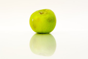 Green apple with reflection on a white background.