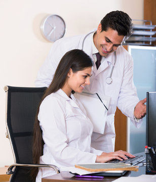 Doctor consulting young intern in clinic office