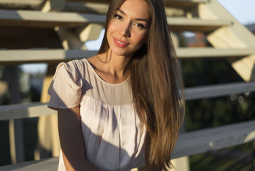 Close-up fashion portrait of a beautiful girl in  pink dress sitting outdoors in bright sunlight, business woman resting enjoy your vacation,  lifestyle sensual brunette long hair tanned skin.