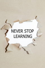 NEVER STOP LEARNING message written under torn paper. 